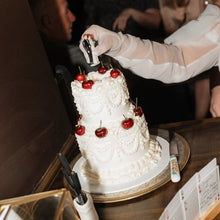 Load image into Gallery viewer, Two tier white on white vintage pearl wedding cake being cut at reception, handmade by Spodeli Newcastle