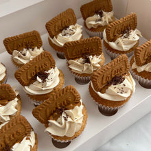Load image into Gallery viewer, A box of cupcakes decorated with piped cream frosting, Lotus biscuit pieces, and dark chocolate sprinkles, arranged inside a white cardboard box.