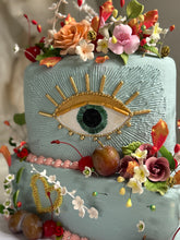 Load image into Gallery viewer, Artistic evil eye cake featuring hand made sugar florals, fruit decoration, gold accents, and textured ganache in a garden inspired design.