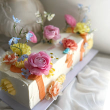 Load image into Gallery viewer, Long table cake decorated with colourful flowers for a wedding celebration