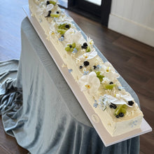 Load image into Gallery viewer, Long rectangular cake with white frosting, green limes, and blackberries on a blue velvet tablecloth.