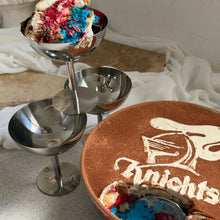 Load image into Gallery viewer, A tiramisu with blue and red layers, served in a silver tiered pedestal bowl and a large round bowl decorated with a knights logo