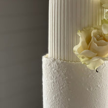 Load image into Gallery viewer, Close-up of stucco-style textured buttercream on the base tier of a cake