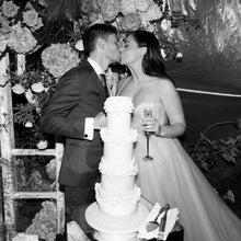 Load image into Gallery viewer, Black and white photo of a tall tiered wedding cake at a wedding