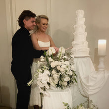 Load image into Gallery viewer, Bride and groom standing beside a tall wedding tower cake