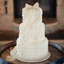 Load image into Gallery viewer, Three-tier fluffy bow cake with textured buttercream and dramatic bow detail
