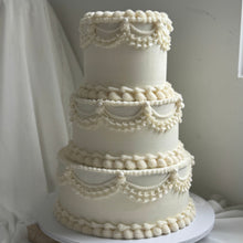 Load image into Gallery viewer, Three-tiered white wedding cake with decorative icing on a plain background
