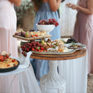 Outdoor gathering with a food display on a table, people in the background
