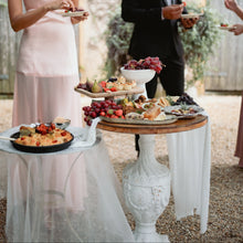 Load image into Gallery viewer, People serving themselves from a buffet table outdoors.
