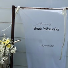 Load image into Gallery viewer, White banner with text on a stand outdoors
