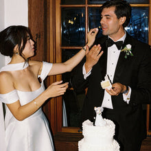 Load image into Gallery viewer, Man and woman in wedding attire cutting a white wedding cake.
