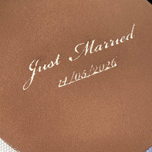 Load image into Gallery viewer, Close-up of a cocoa-dusted tiramisu wedding cake with “Just Married” and the wedding date elegantly stencilled across the top in icing sugar.
