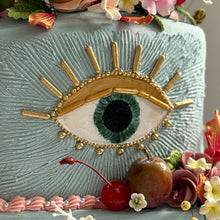 Load image into Gallery viewer, Close-up of The Gilded Evil Eye Garden Cake showing the hand painted cocoa butter eye, gold detailing, textured ganache, and fruit accents.
