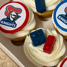 Load image into Gallery viewer, Close-up of frosted cupcakes topped with lego. One cupcake has a white frosting swirl and a round topper featuring the newcastle knights logo.
