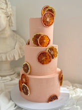 Load image into Gallery viewer, Close-up of dried citrus detailing on a euro-inspired tiered cake
