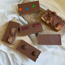 Load image into Gallery viewer, Assorted chocolate slices on a textured surface
