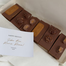Load image into Gallery viewer, A gift box of homemade slices with a handwritten card The slices are decorated with biscuit pieces and ferrero and are set against a clean white background.
