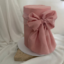 Load image into Gallery viewer, Pretty in pink bow cake with a sculptural fabric-style bow, finished as a single tier double height cake for modern celebrations
