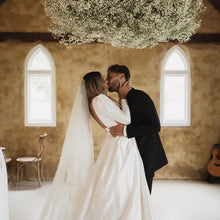 Load image into Gallery viewer, Couple embracing in wedding venue representing save the date cake booking
