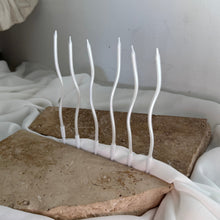Load image into Gallery viewer, Slim white wavy candles standing on stone styling blocks in soft natural light
