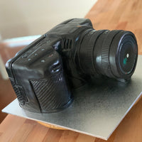 Side view of a sculpted camera cake highlighting hand-built structure
