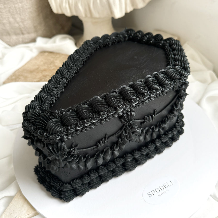Black Coffin shaped cake with detailed hand piping and sculptural form