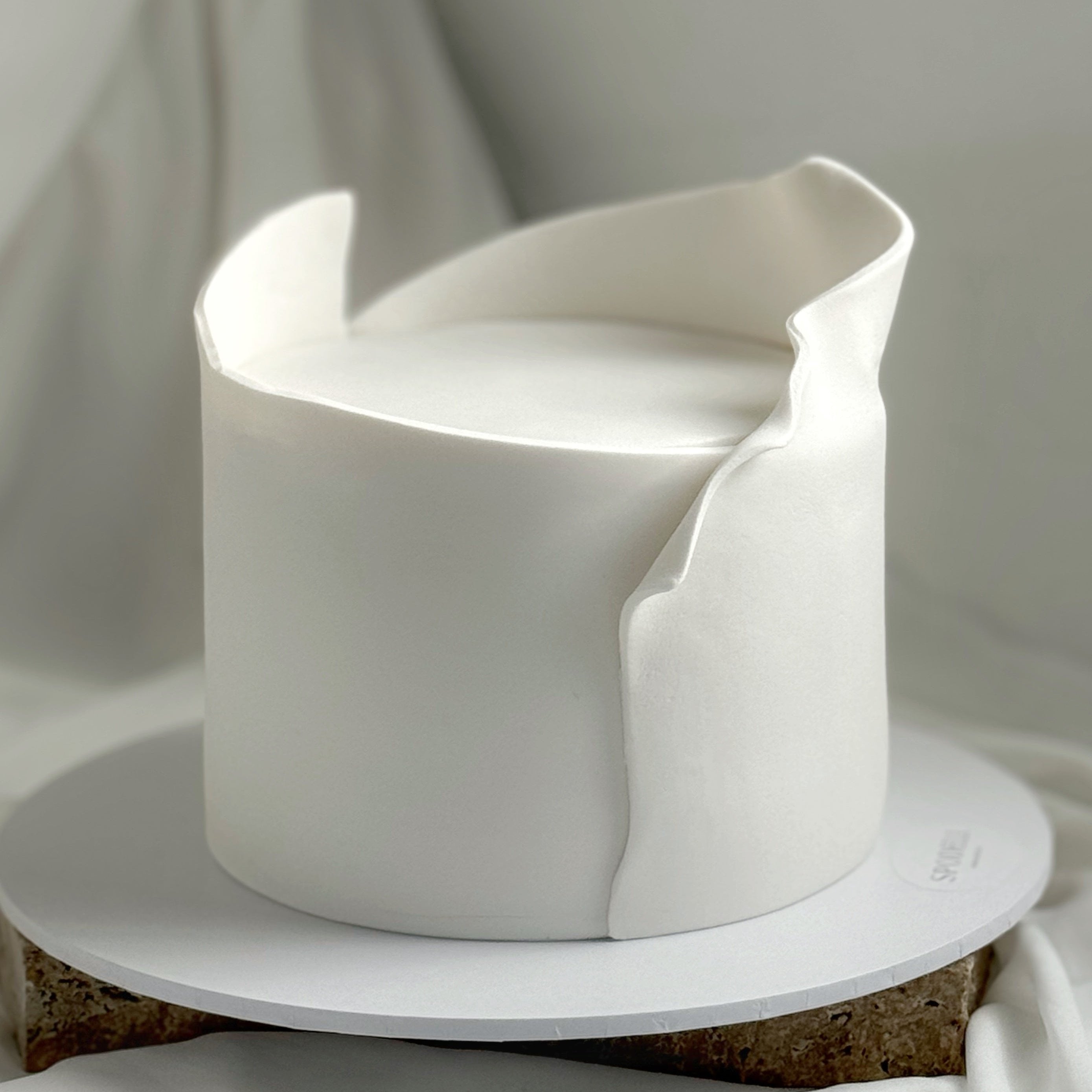 Wrapped in Love sculptural white cake with wrapped fondant finish for intimate celebrations